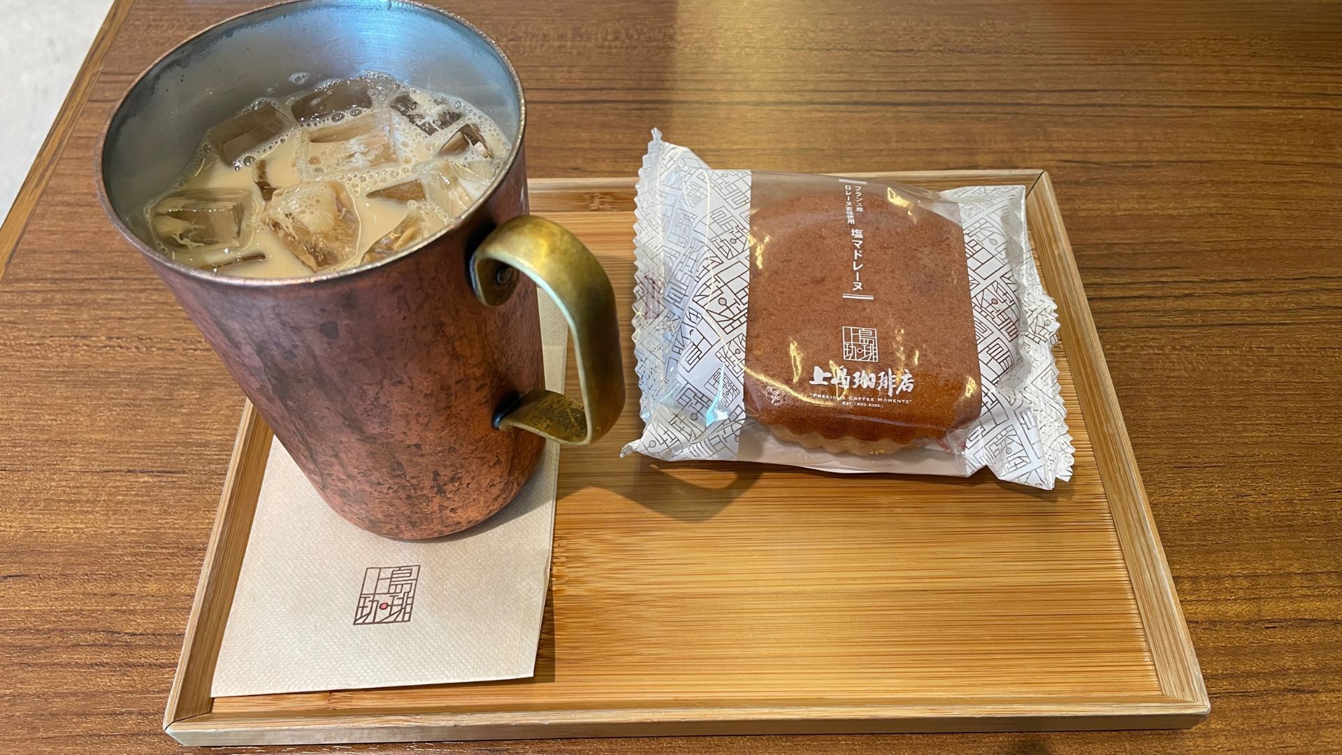 Plateau en bois avec tasse de lait glacé et madeleine